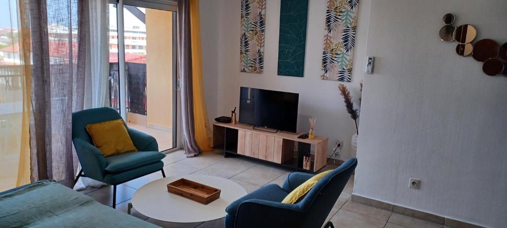 a living room with a couch and chairs and a tv at NANA A33 Appartement 2 Chambres Climatisées cuisine équipée Netflix in Cayenne