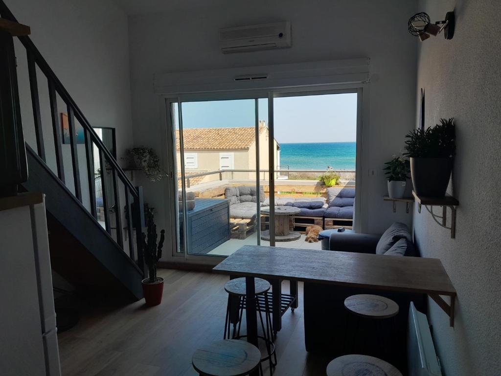 - un salon avec une table et une vue sur l'océan dans l'établissement Le Sablé, à Frontignan