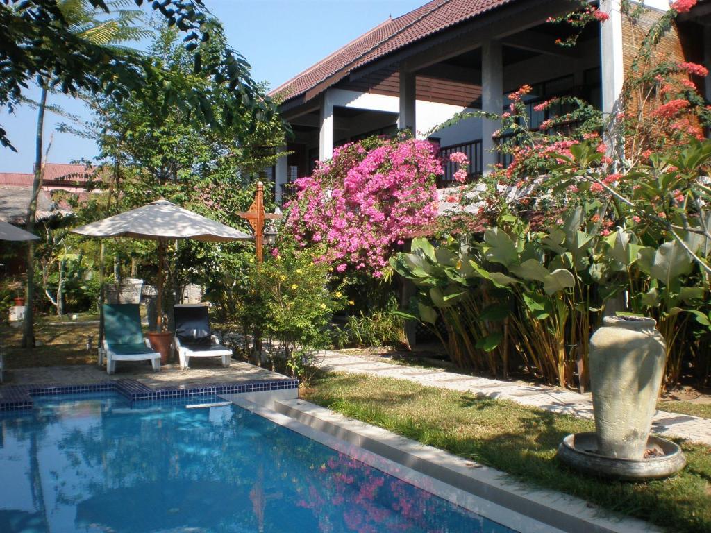 a swimming pool in front of a house with flowers at Villa Molek in Pantai Cenang