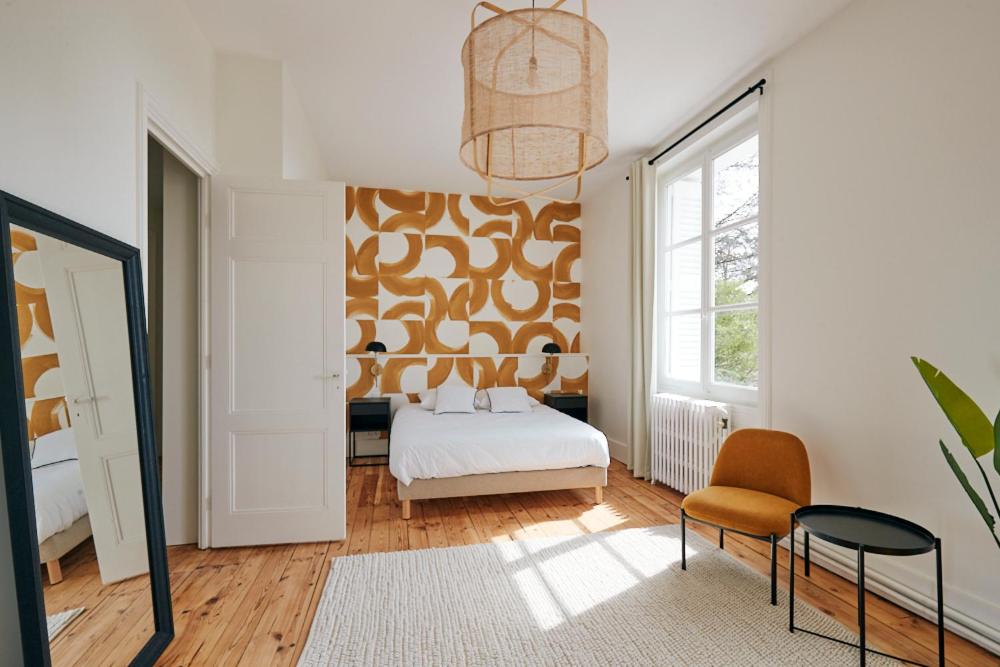 a bedroom with a bed and a chair and a window at Maison Martouret - Colodge in Andrézieux-Bouthéon