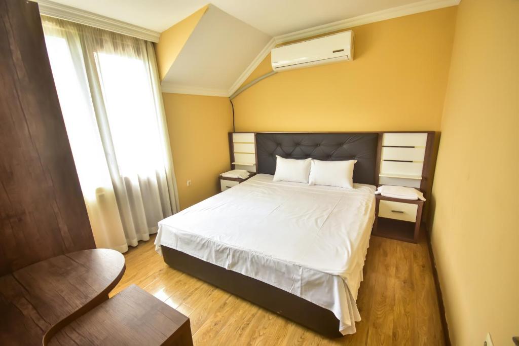 a bedroom with a bed with white sheets and a window at Family Apartments in Batumi in Batumi