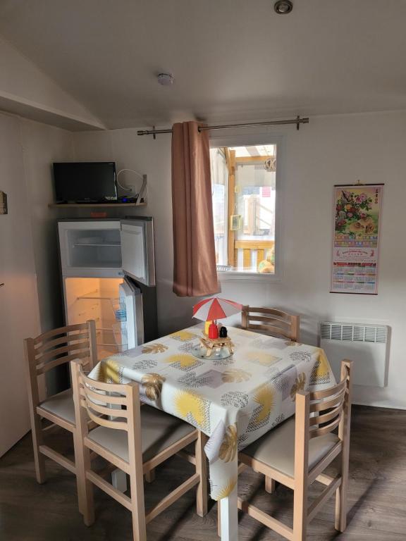 a dining room table and chairs with a table and a window at Mobil home 6 personnes in Saint-Brevin-les-Pins