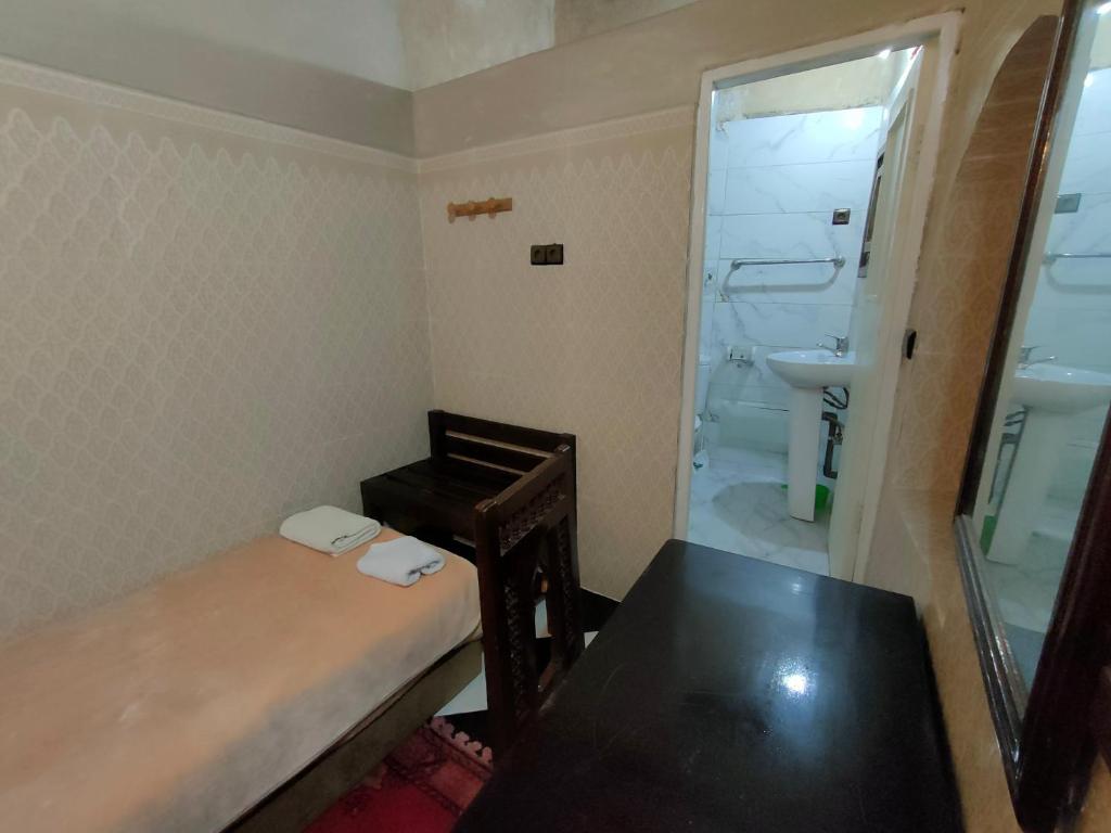 Cette petite chambre comprend une table et une salle de bains. dans l'établissement RIAD Tamazouzt, à Essaouira