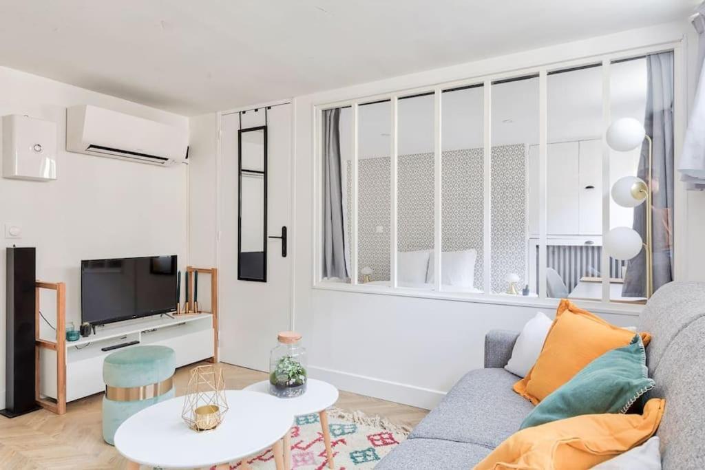 ein Wohnzimmer mit einem Sofa und einem TV in der Unterkunft Appartement proche Arc Triomphe 4P in Paris