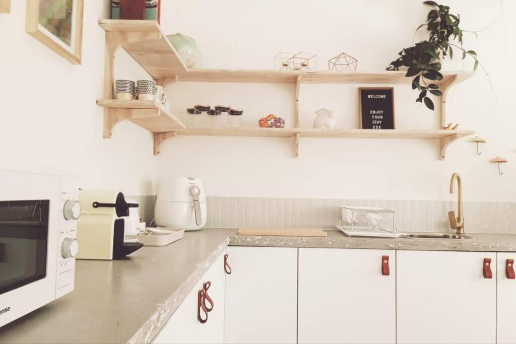 a kitchen with white cabinets and a microwave at Stylish family unit in Walmer in Gqeberha