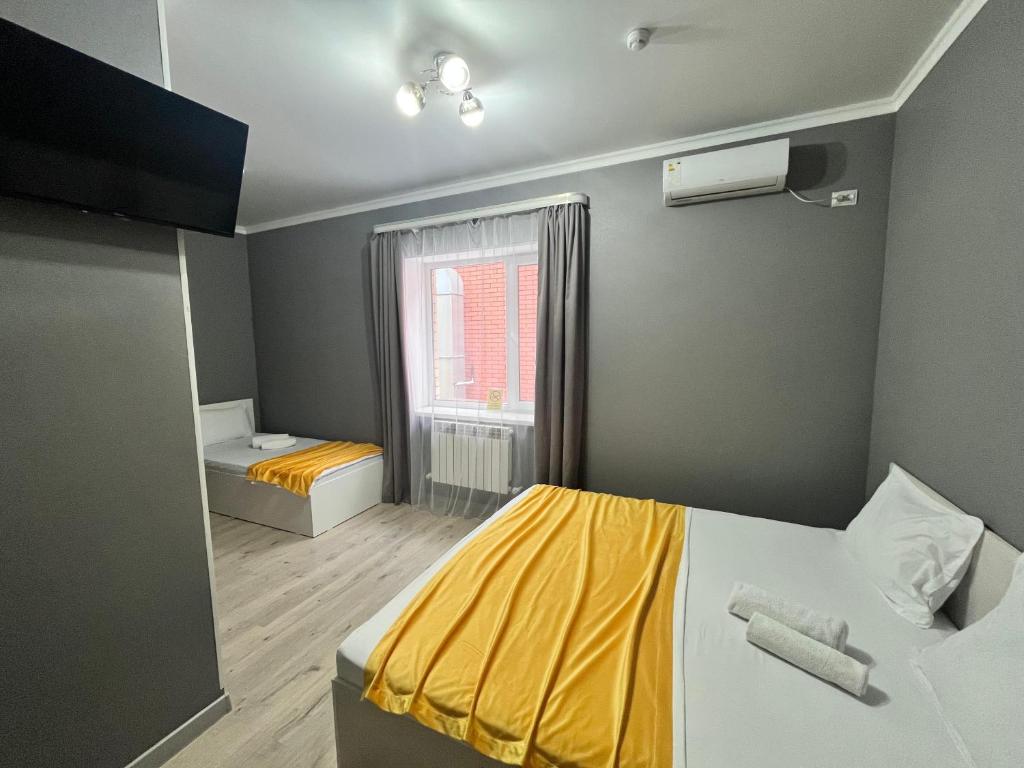 a small bedroom with a yellow bed and a window at Мини-гостиница Береке in Aktobe