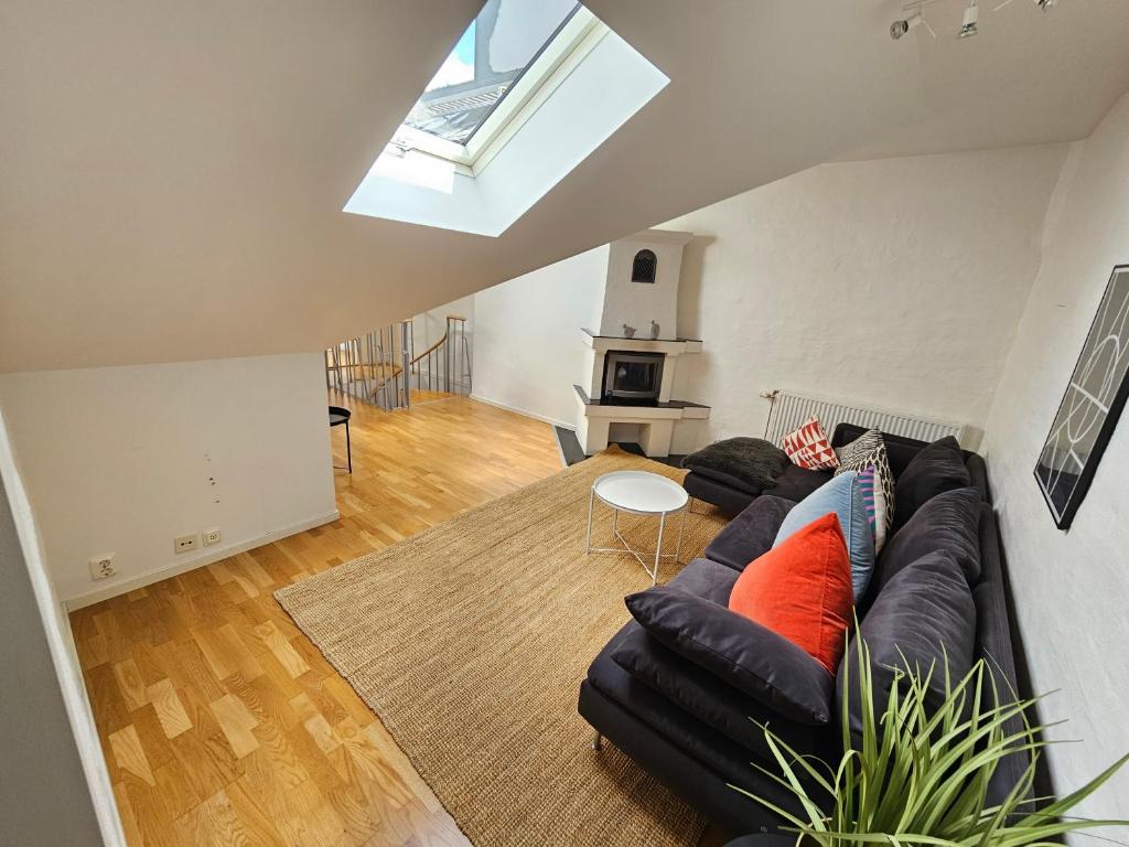 een woonkamer met een zwarte leren bank en oranje kussens bij Home Inn KG26 in Stockholm