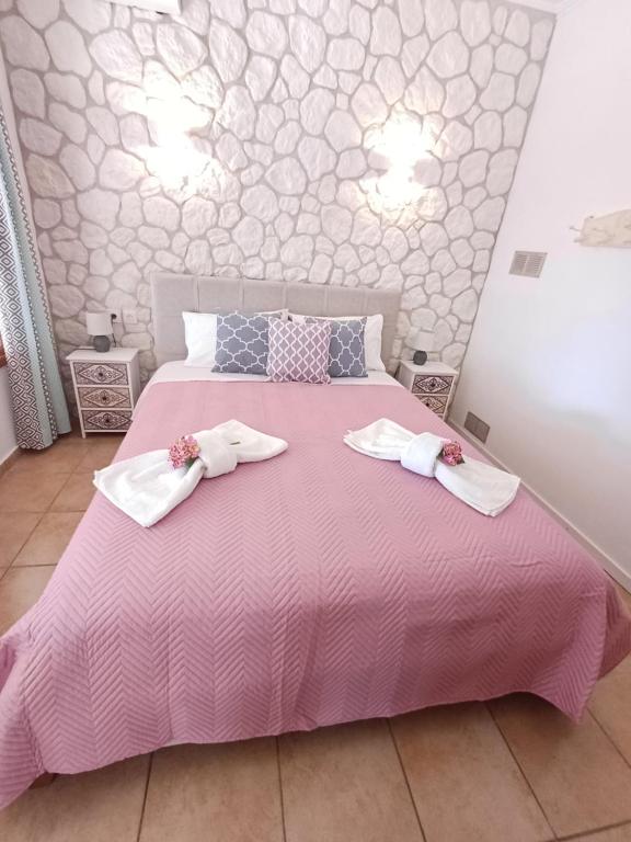 a bedroom with a pink bed with two towels on it at Kiki's Apartments in Barbati