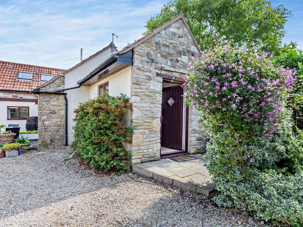 un cottage en pierre avec une porte marron et des fleurs dans l'établissement 1 Bed in Wedmore 51337, à Chapel Allerton