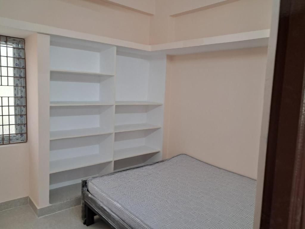 a bedroom with white shelves and a bed in it at Srinivasa Nilayam in Hyderabad