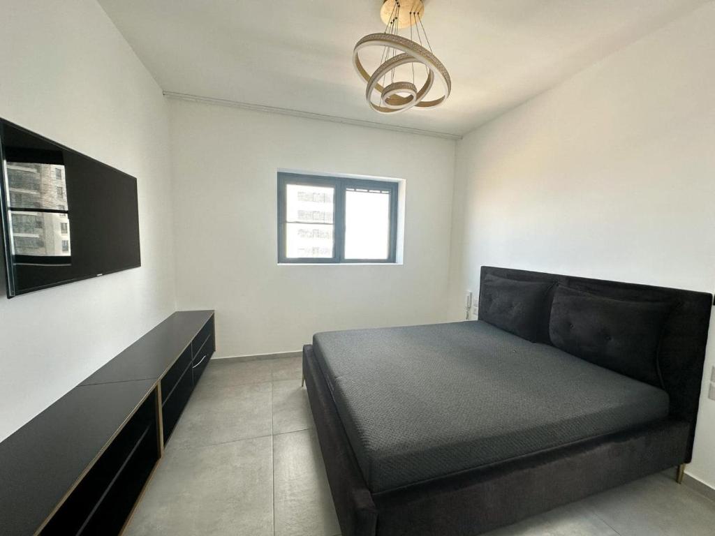 1 dormitorio con 1 cama y 1 sofá negro en O&O Group -Stellar Luxury 4BR APT en Bat Yam