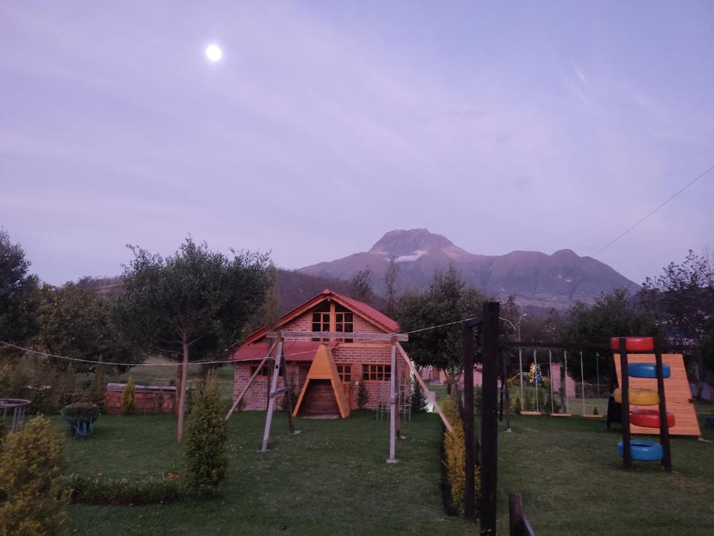 a playground in front of a house with a building at Cabañas Tecla María in Otavalo