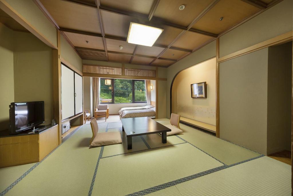 水上町聚乐水上日式旅馆的客厅配有桌子和电视