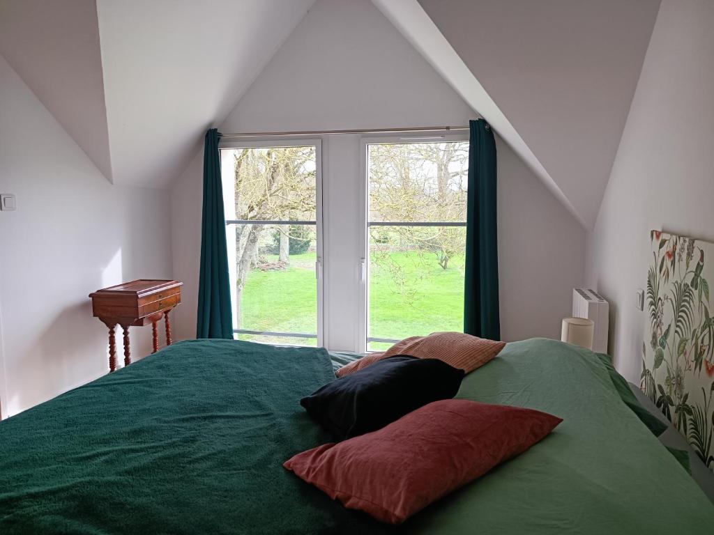 Un dormitorio con una cama verde con almohadas y una ventana en Gîte à côté de " la Java bleue" en bord de rivière, en Amanlis