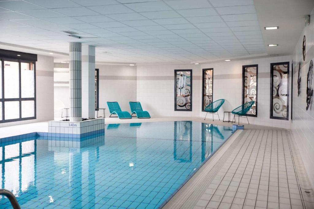 una piscina con sillas azules en un edificio en Clarion Aparthotel Toulouse Blagnac Airport en Blagnac