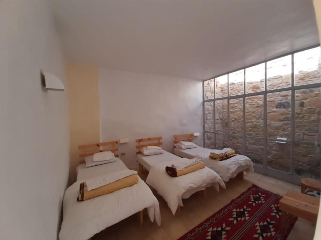 a room with four beds and a large window at Fig tree hotel in Dana