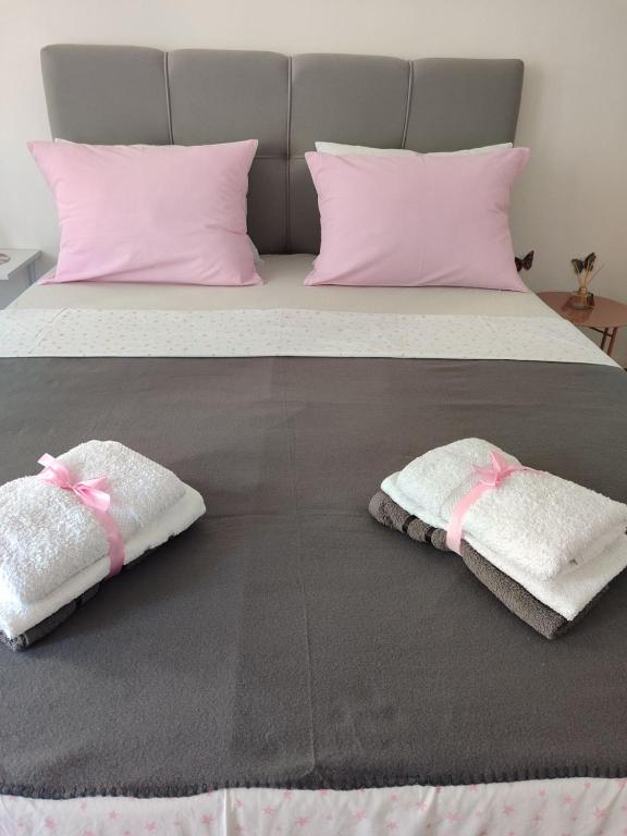 two towels on a bed with pink pillows at Flowers Apartment Tuzla in Tuzla