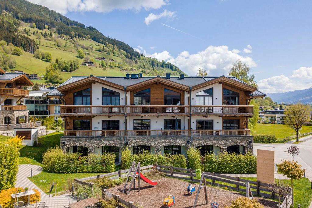 a large building with a playground in front of it at Tauernsuites Mitterwirt by ALPS RESORTS in Piesendorf