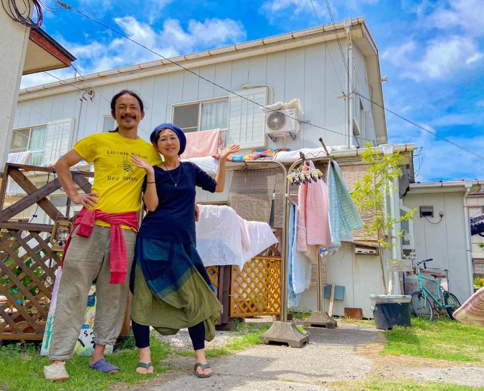 un hombre y una mujer parados frente a una casa en ゲストハウス千倉のおへそ, en Chikura