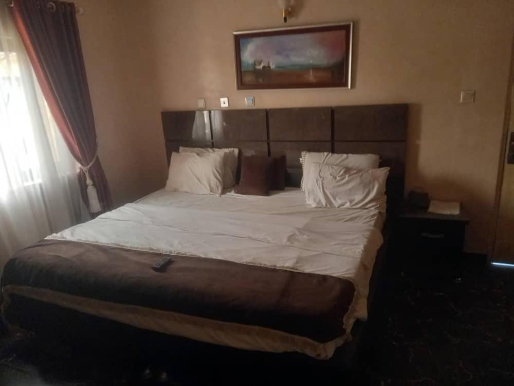 ein Schlafzimmer mit einem großen Bett mit weißer Bettwäsche und Kissen in der Unterkunft The Resident Hotel in Owerri