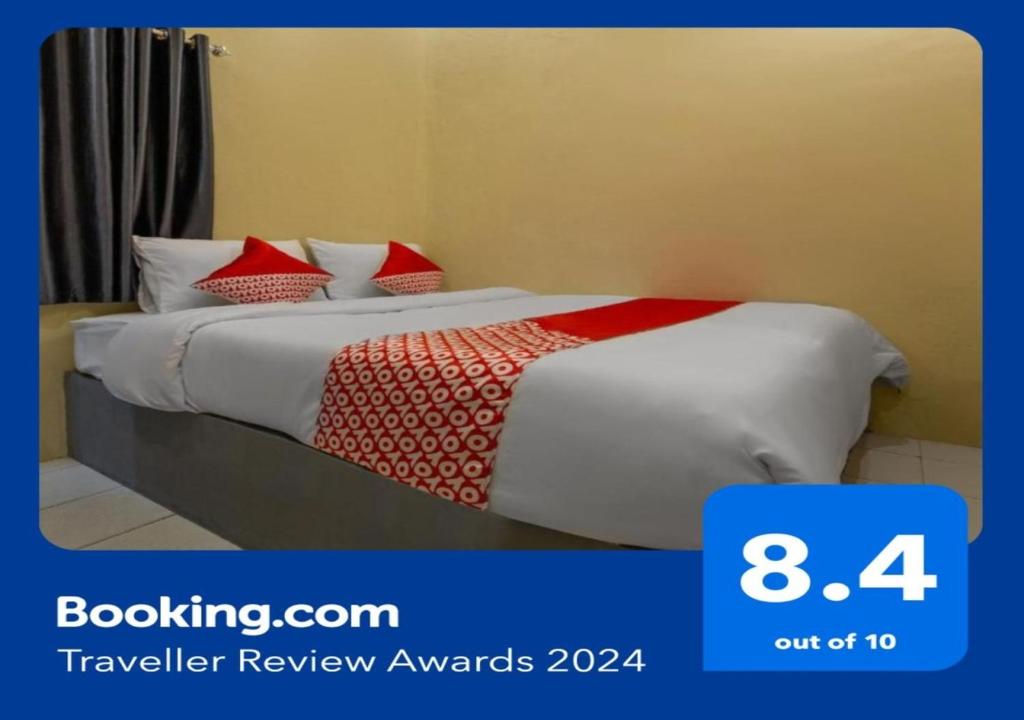 a hotel room with a bed with red and white pillows at OYO 2527 Hotel Triana in Palangkaraya