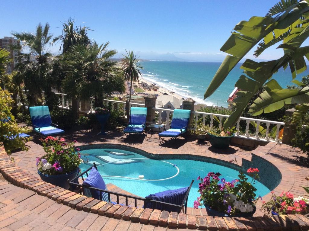 a swimming pool with chairs and the beach at A Heavenly View in Muizenberg
