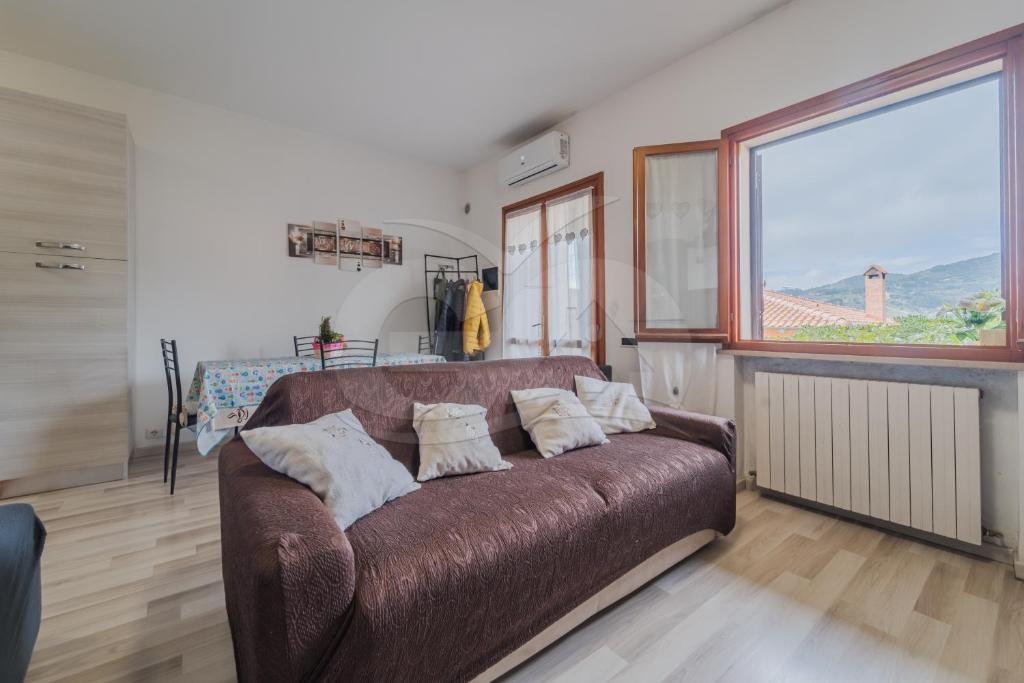 um sofá castanho num quarto com uma grande janela em Trilocale Nicole - Goelba em Porto Azzurro