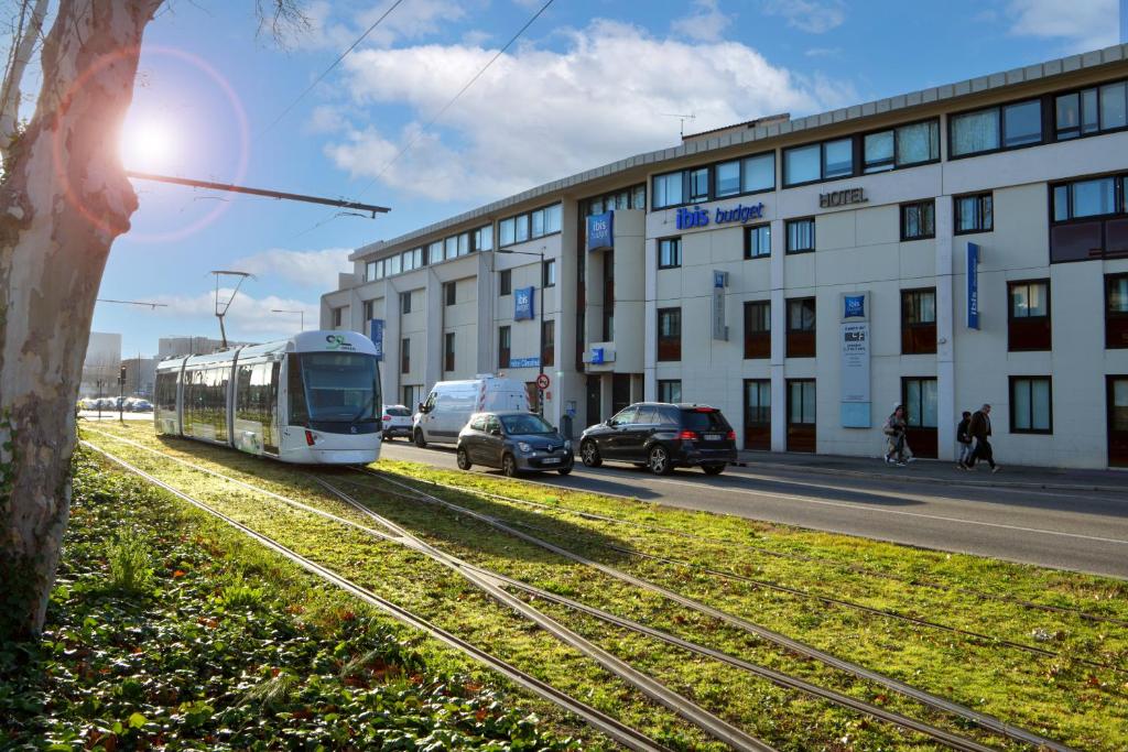 a train on the tracks in front of a building at ibis budget Avignon Centre in Avignon