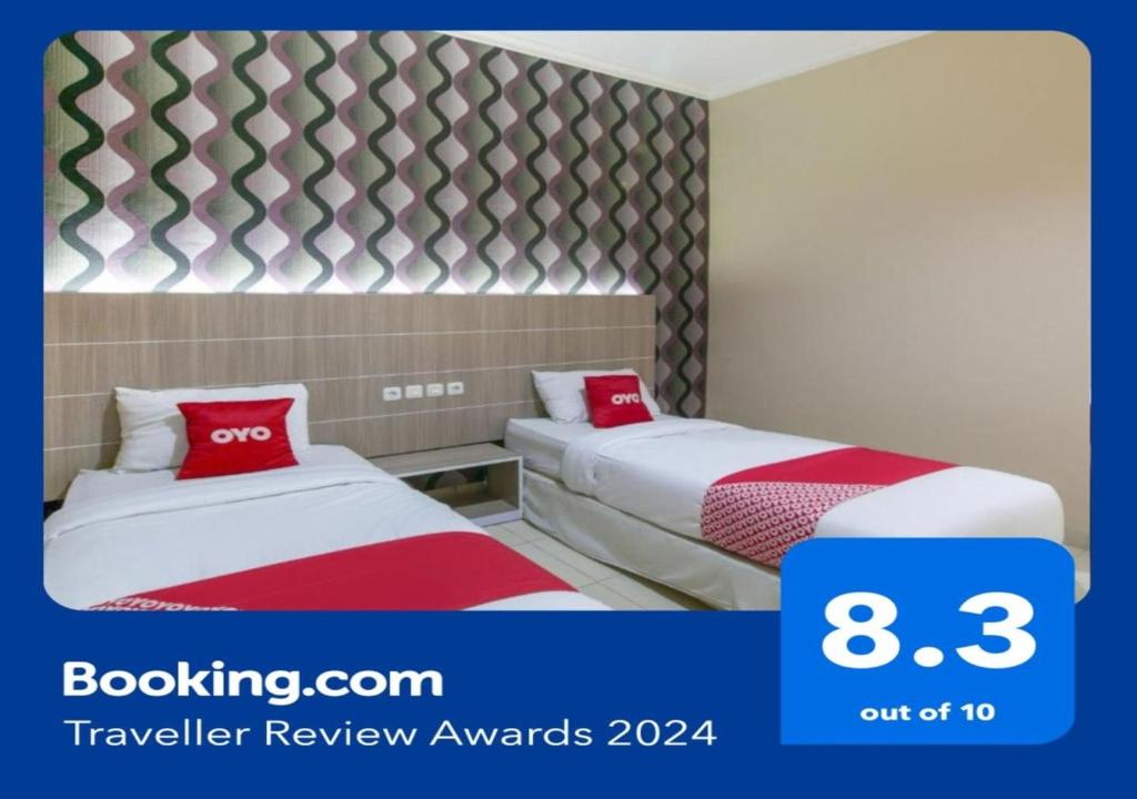 Cette chambre d'hôtel comprend 2 lits avec des oreillers rouges. dans l'établissement SUPER OYO 2320 Hotel Charvita, à Kupang
