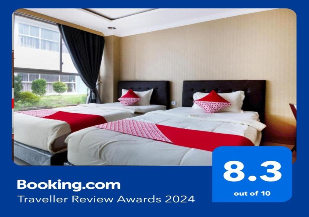 duas camas num quarto de hotel com lençóis vermelhos e brancos em Super OYO Collection O 3431 Hotel Alpha Bandara em Palimbão