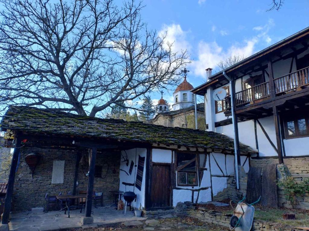 a white house with a white horse standing in front of it at Hadjigabarevata Kashta in Dalbok-Dol