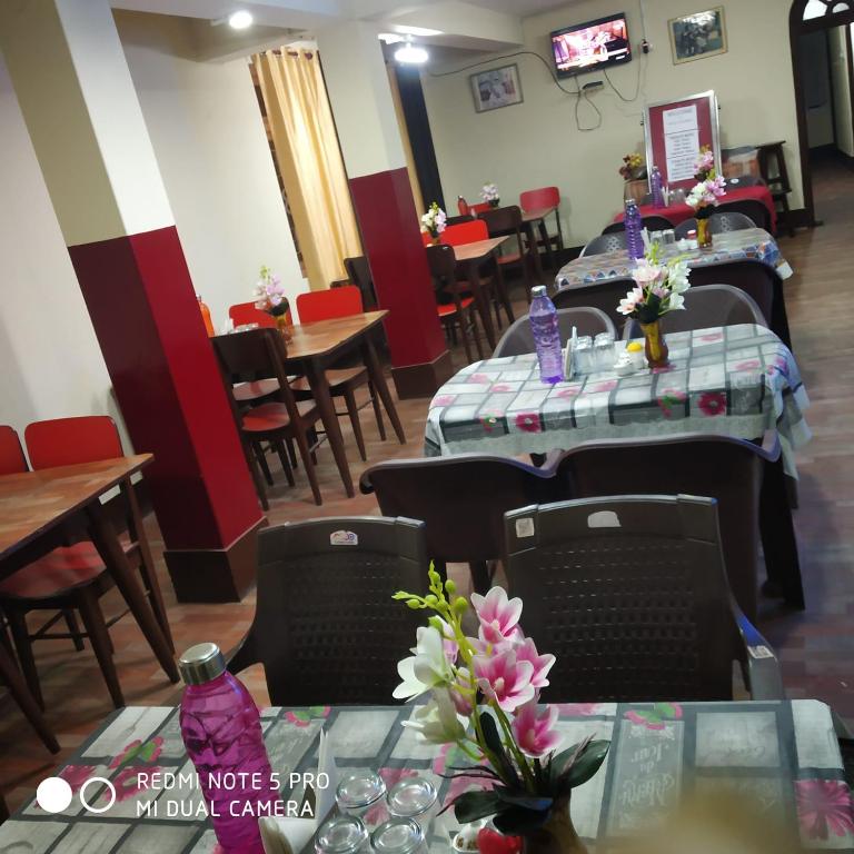 a dining room with tables and chairs with flowers on them at HOTEL TASHI NORLING Near Mall Road in Gangtok
