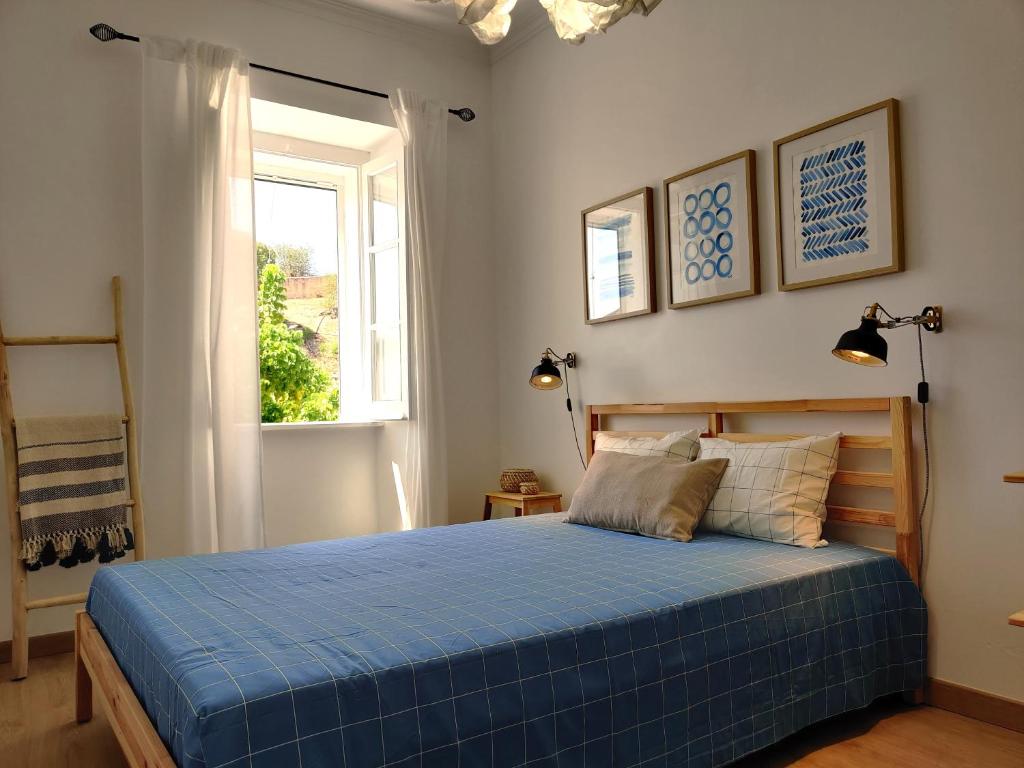 a bedroom with a blue bed and a window at Largo A2 in Alcácer do Sal