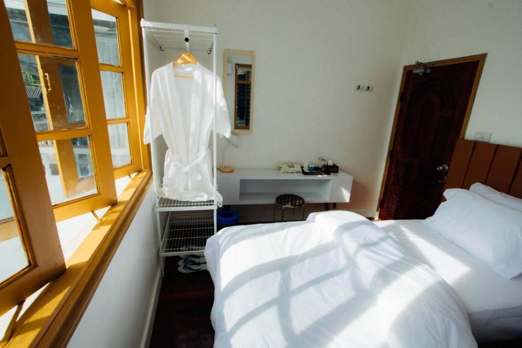 a bedroom with a bed and a white shirt on a rack at S Money in Rong Sak