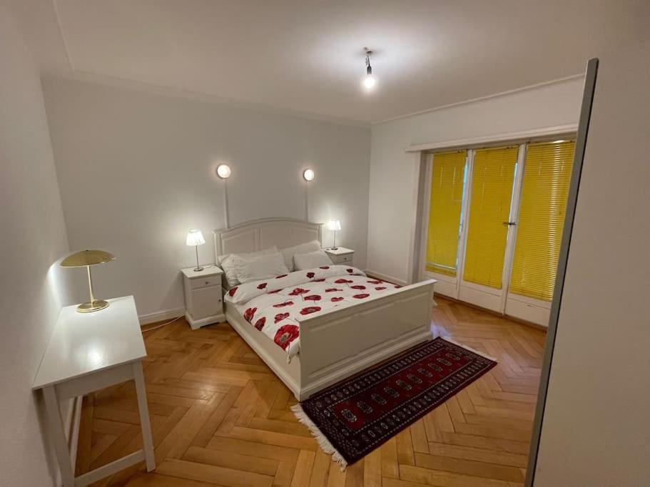 Appartement élégant & ensoleillé في لوزان: غرفة نوم بسرير وطاولة ونافذة