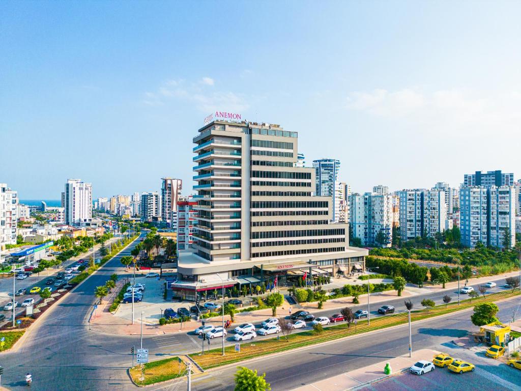 een stad met een hoog gebouw en een straat met auto's bij Anemon Mersin Hotel in Çiftlikköy