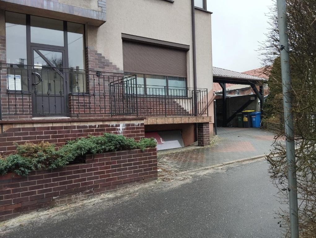 a brick house with a balcony and a driveway at Apartament dla par in Olesno