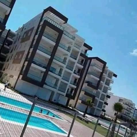 a tall building with a pool in front of it at Résidence Amwej in Port El Kantaoui