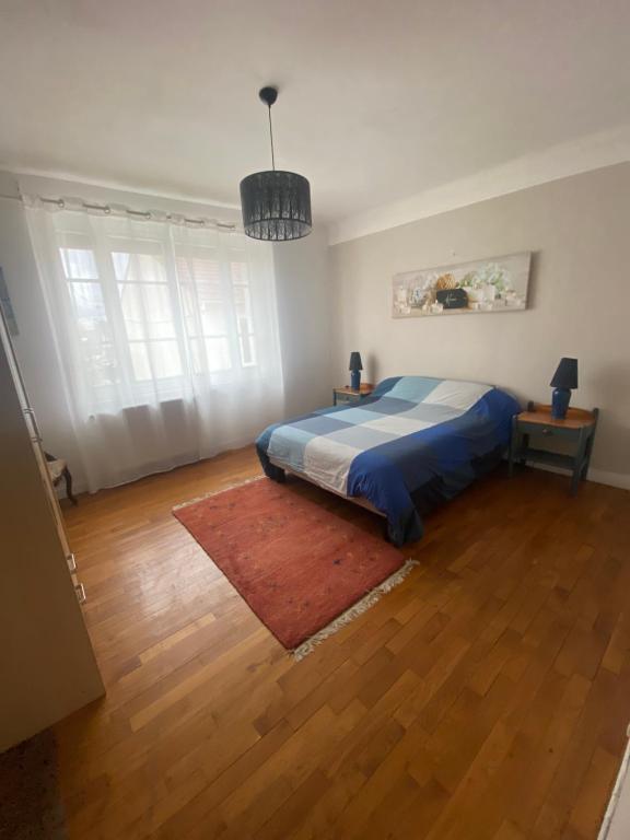 a bedroom with a bed and a rug on a wooden floor at appartement de 50m2 grand et spacieux avec jardin in Viry-Châtillon