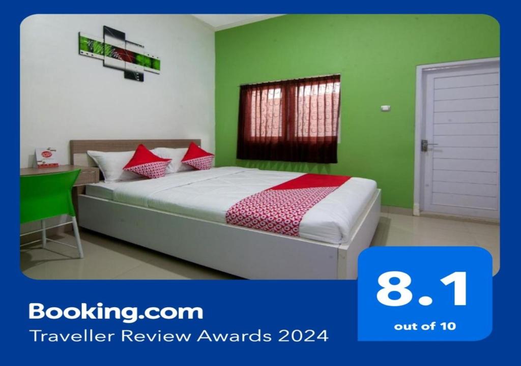 een slaapkamer met groene muren en een bed met rode kussens bij Super OYO 2808 D'residence Syariah in Tegal