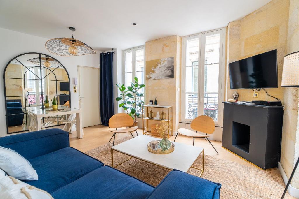 a living room with a blue couch and a tv at Charmant appartement haut de gamme in Bordeaux