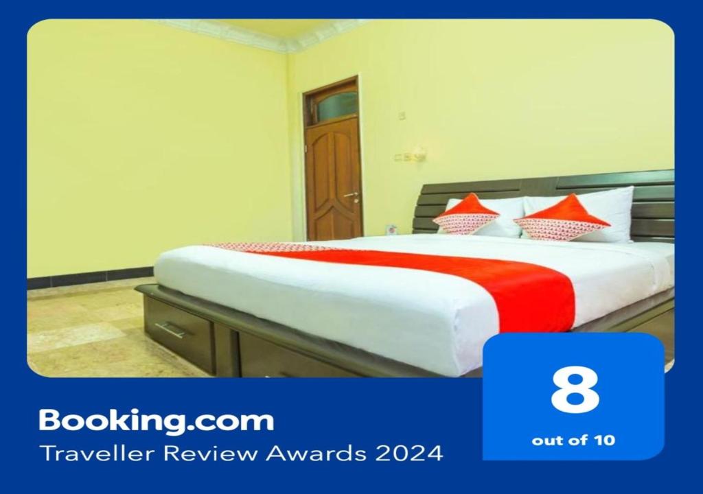 a hotel room with a bed with red and white pillows at OYO 2848 Senaz Guesthouse in Mataram