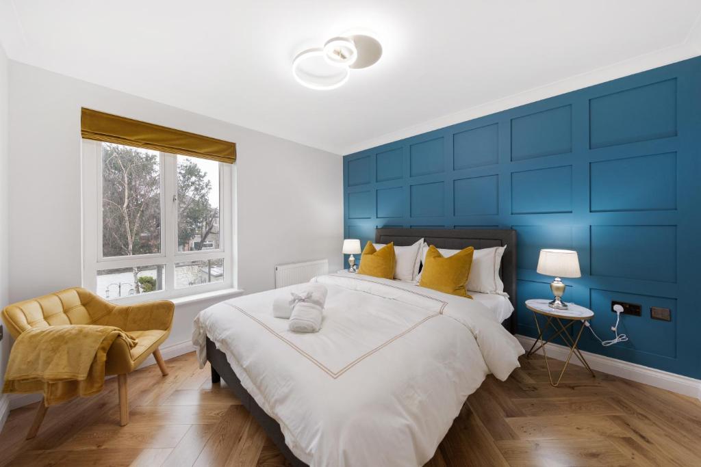 1 dormitorio azul con 1 cama grande y 1 silla en Spacious Stunning Flat near Heathrow and Central London, en Hounslow
