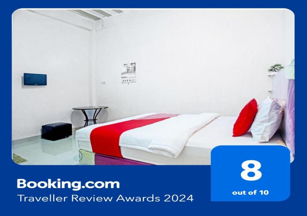 um quarto de hotel com uma cama com lençóis vermelhos e brancos em OYO Life 90587 Domen Homestay Syariah em Krui