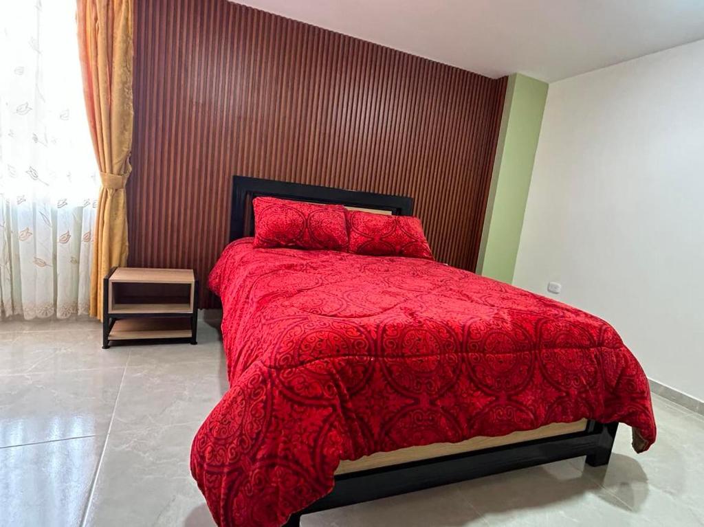 a bedroom with a red bed with a red comforter at Hotel Colonial House in Pasto