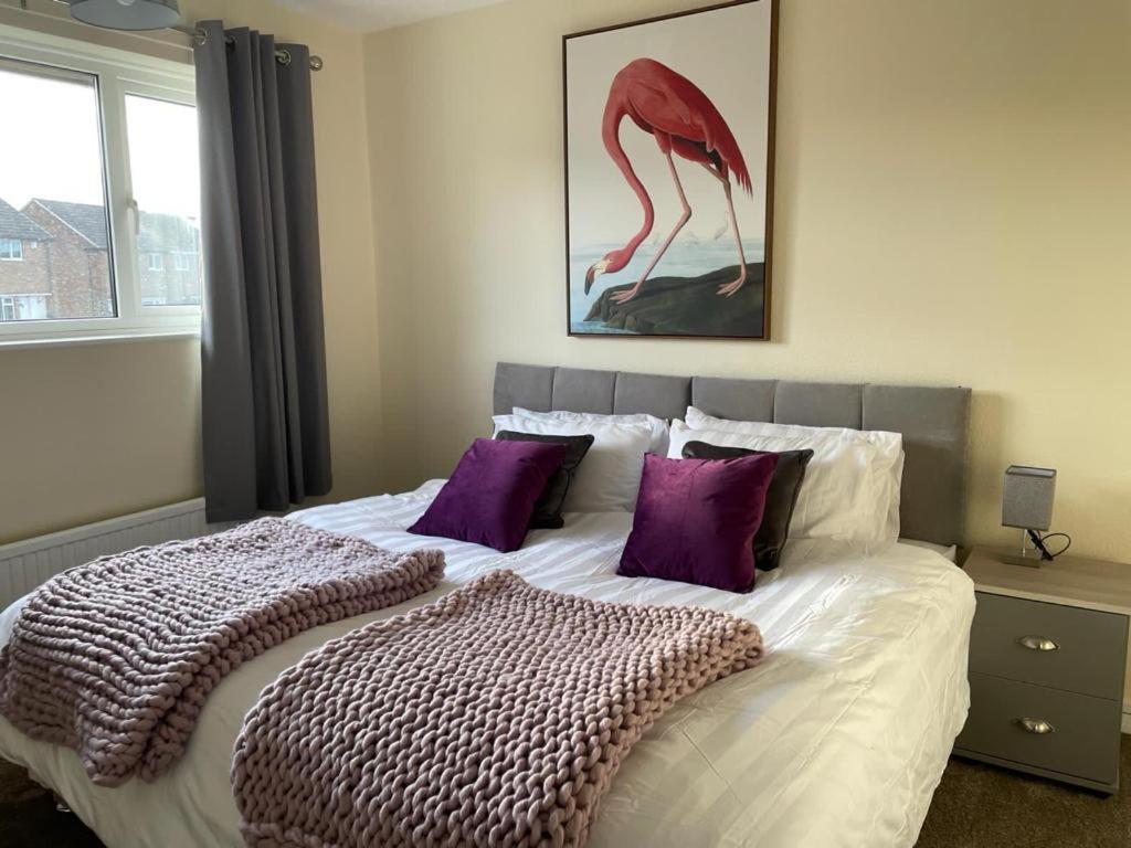 a bedroom with a large bed with purple pillows at Stunning 3 bedrooms house with Garden and Free Parking in Barnsley