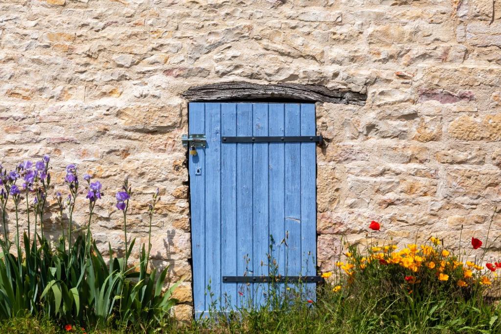 Sennecey-le-GrandにあるAuberg'Innの花の石造りの建物の青い扉