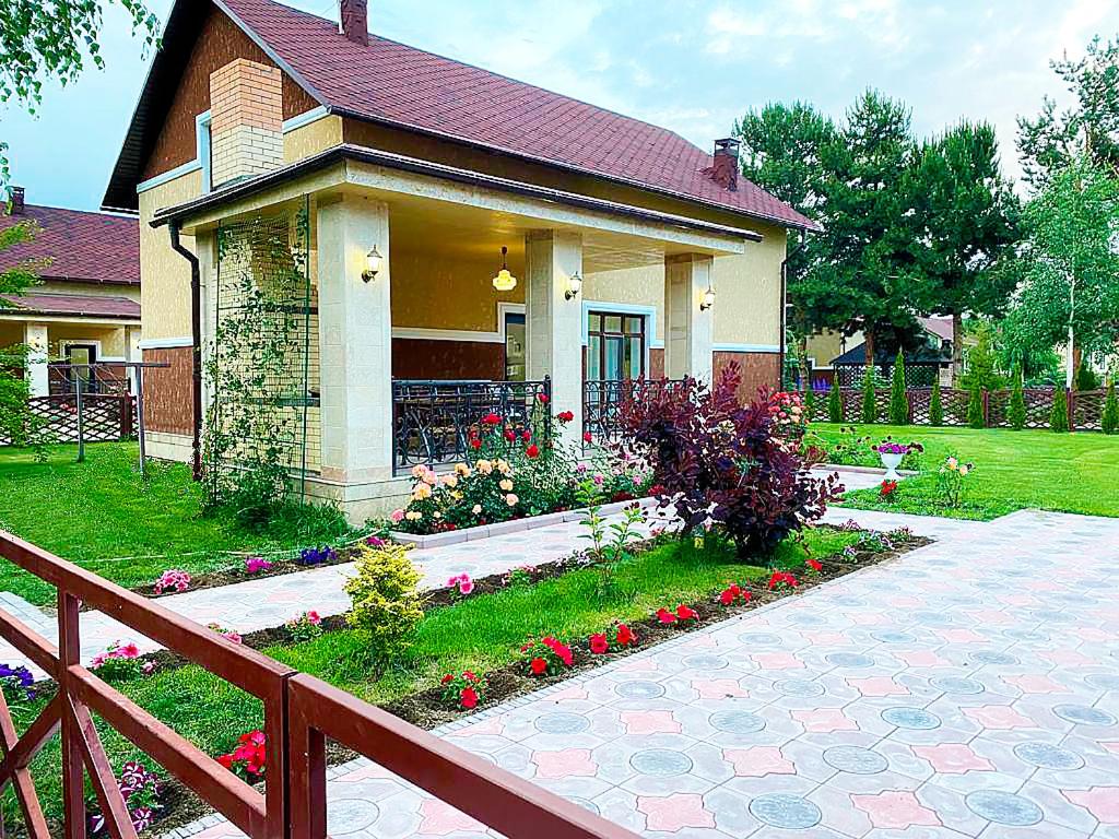 a small house with a porch and flowers in the yard at Центр Отдыха Лазурный берег in Chok-Tal
