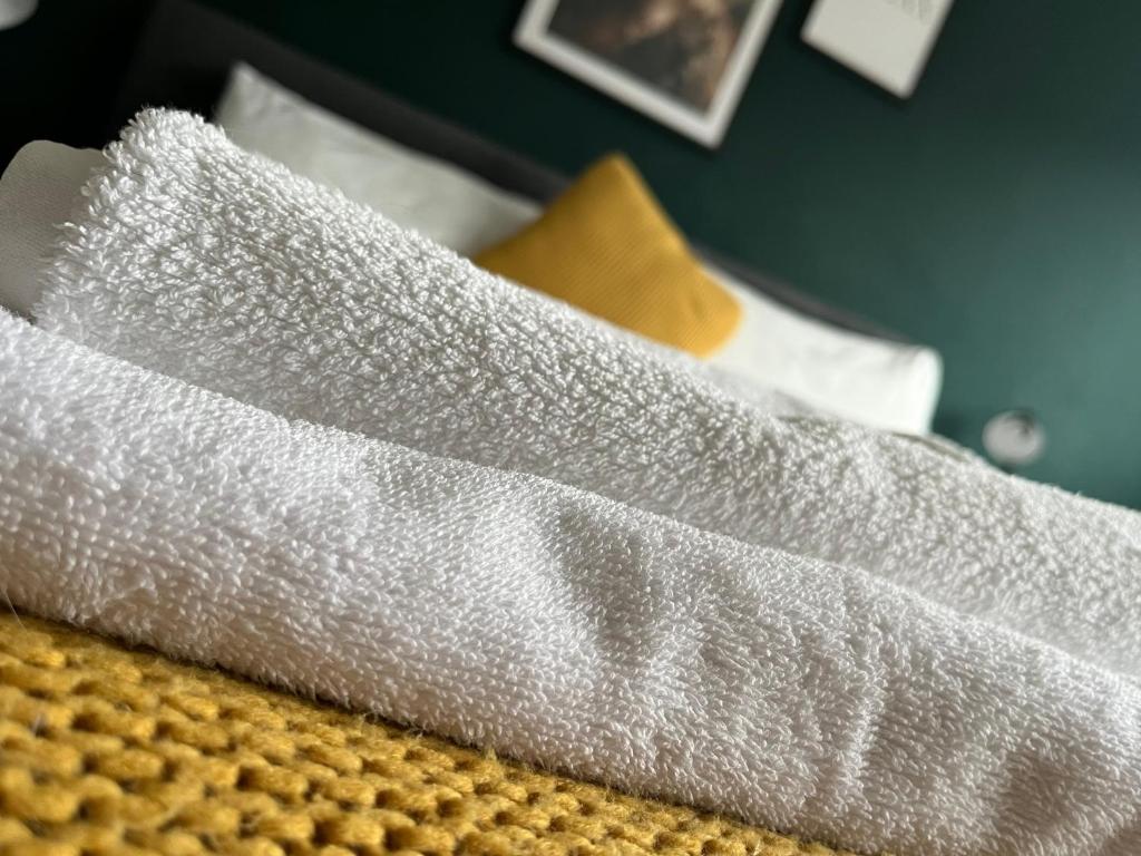 una pila de sábanas blancas encima de una cama en Durham 3 Bedroom House With Parking en Durham
