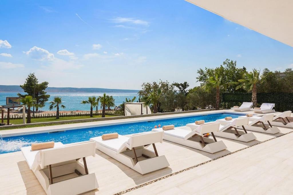 uma piscina com espreguiçadeiras brancas e uma piscina em Exclusive Villa Calma I - heated pool&spa sea view em Starigrad-Paklenica